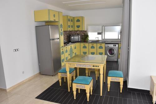 a yellow kitchen with a table and chairs and a refrigerator at Arabesque Style - 2 appartements in Kelibia