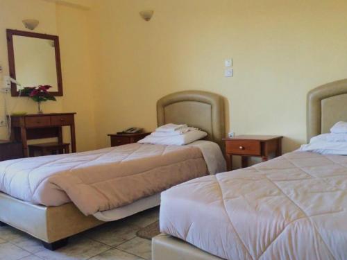 a hotel room with two beds and a mirror at Ξενοδοχείο "Ηραία" in Iamatikes Piges