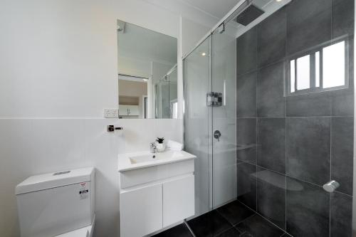 y baño blanco con lavabo y ducha. en Renovated Little Cottage Aberdare Hunter Valley, en Aberdare