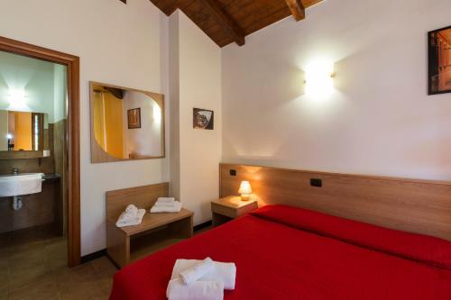 a bedroom with a red bed and a bathroom at Residence Montebello in Bolano