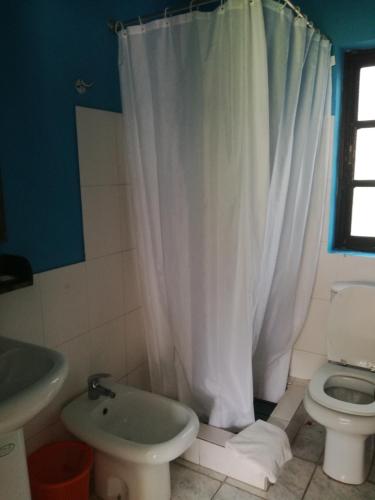 a bathroom with a white shower curtain and a toilet at Aldeia Jerome in Paul