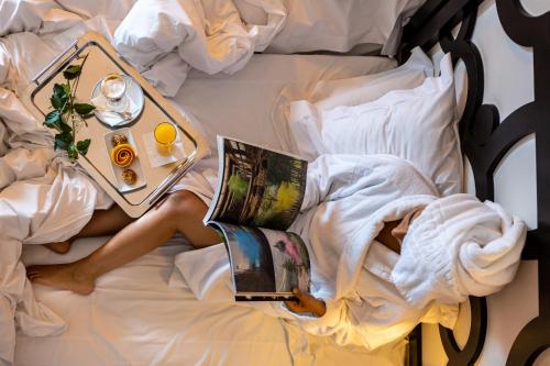 a person laying on a bed with a tray of food at Pousada Convento de Tavira in Tavira