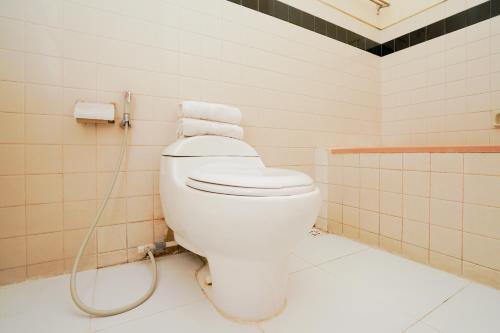 a bathroom with a white toilet with a hose at OYO 1652 Hotel Tampiarto in Probolinggo