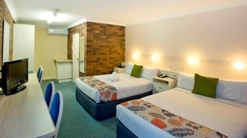 a hotel room with two beds and a tv at Best Western Parkside Motor Inn in Coffs Harbour