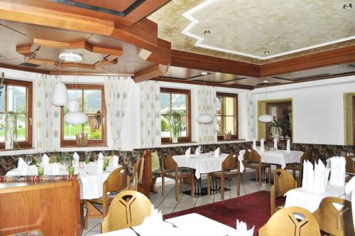a restaurant with white tables and chairs and windows at Gasthof Schopper in Breitenbach am Inn