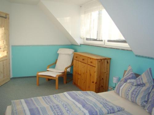 um quarto com uma cama, uma cadeira e uma janela em Ferienhaus zu Wohlsborn em Wohlsborn
