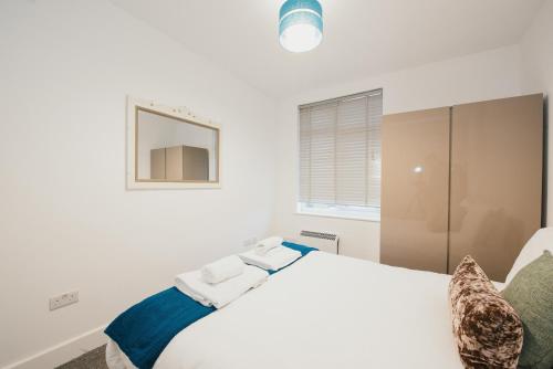 a white bedroom with a bed and a mirror at Home Sweet Home by Paymán Club in Cambridge