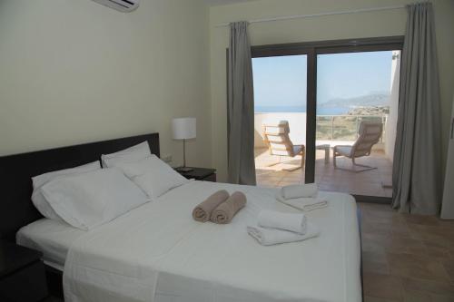 a bedroom with a white bed with a view of the ocean at Lagada Resort in Makry Gialos