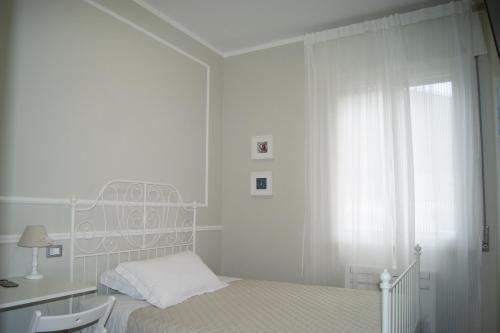 a white bedroom with a bed and a desk and a window at LA DAMA ROOM&BREAKFAST in Russi