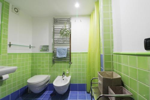 ナポリにあるCasa Maria Carmelaの緑のタイル張りのバスルーム(トイレ、シンク付)