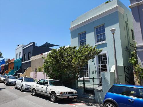 a white car parked in front of a blue building at De Waterkant Cottages in Cape Town