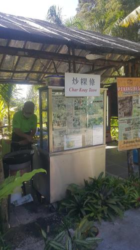 a man sitting at a food stand with a sign at Bellevue The Penang Hill Hotel, Bukit Bendera in Ayer Itam