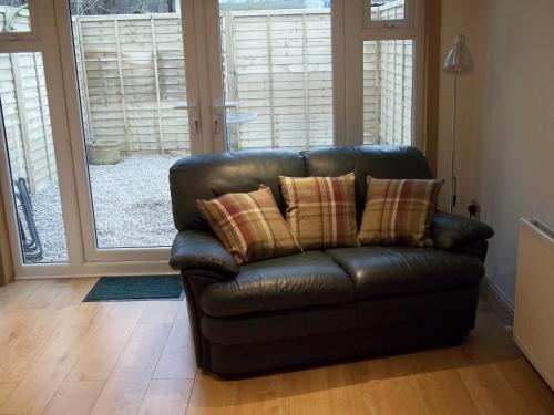 a leather couch with pillows in a living room at The Wee Thistle Loch Ness in Drumnadrochit