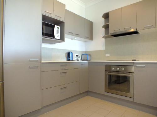 a kitchen with white cabinets and a microwave at Pacific Marina Apartments in Coffs Harbour