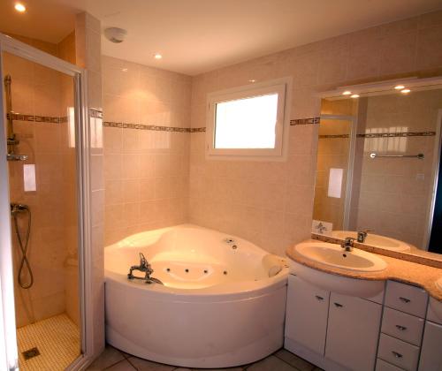 a bathroom with a large tub and a sink at Lagrange Vacances - Atlantic Green in Lacanau-Océan