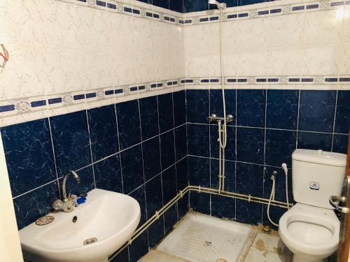 Baño de azulejos azules con aseo y lavamanos en Auberge Alferdaous, en Tataouine