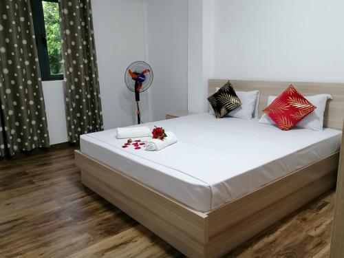 a bedroom with a large white bed with red and black pillows at Bobato building in Curepipe