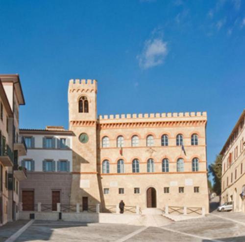 un grand bâtiment en briques avec une tour d'horloge dans l'établissement Tavernetta vicino Lago Trasimeno, à Magione