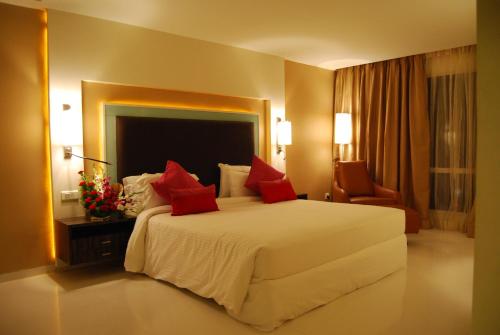 a bedroom with a large white bed with red pillows at Royal Park Kakinada in Kākināda