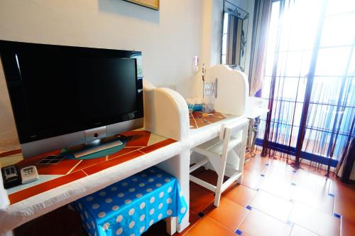 a living room with a television on a table with chairs at 海灘戀情 Beach Love 近沙灘-國旅卡特約商店 陽台房 希臘地中海風格 in Eluan