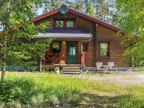 drewniany domek z zielonymi drzwiami i krzesłami w obiekcie Holiday Home Villa salix by Interhome w mieście Mäntyharju