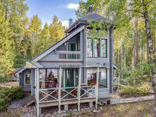 a house in the woods with a wrap around porch at Holiday Home Villa populus by Interhome in Pertunmaa