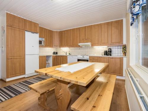 une cuisine avec des placards en bois, une table et des bancs en bois dans l'établissement Holiday Home Oriaho by Interhome, à Iisalmi