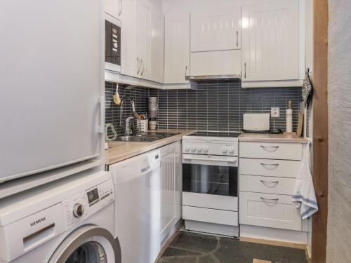 a kitchen with white cabinets and a washer and dryer at Holiday Home Vuokatinportti b 8 by Interhome in Vuokatti