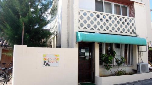 a white building with a sign on the side of it at ゲストハウスこねくと in Ishigaki Island