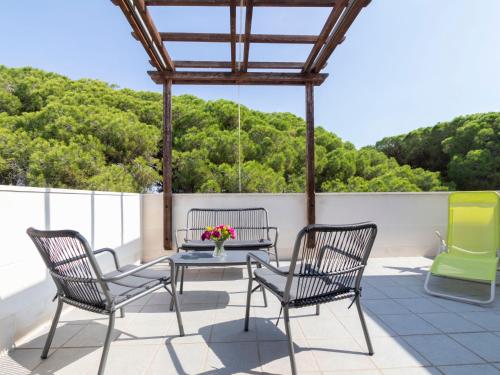 a patio with three chairs and a table with flowers on it at Holiday Home Sol Cambrils Park-6 by Interhome in Cambrils