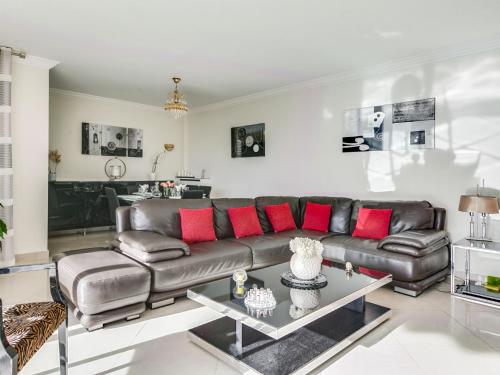 salon ze skórzaną kanapą i czerwonymi poduszkami w obiekcie Apartment Les Pins D'Alep by Interhome w mieście Le Cannet
