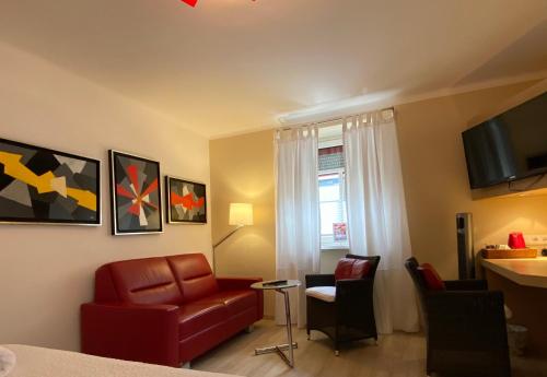 a living room with a red couch and a chair at Bergland Hotel - Adults only in Salzburg