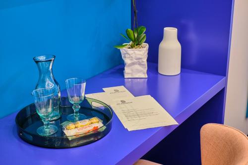 a blue table with a tray with glasses and a bottle at Vilacrosse Boutique Inn in Bucharest