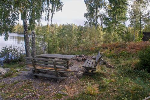 two benches and a picnic table next to a lake at Haus Fegensee in Kalv
