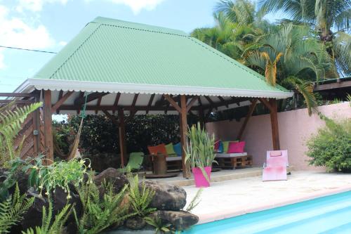 a gazebo with colorful chairs and a pool at Gite bagatelle classé 2 étoiles in Sainte-Rose