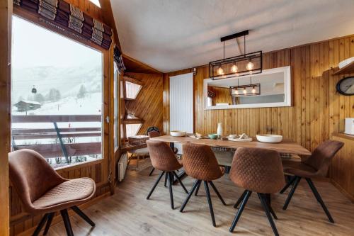 une salle à manger avec une table et des chaises et une fenêtre dans l'établissement Le Santel 199, à Val dʼIsère