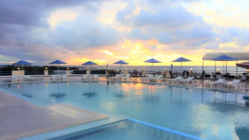 a large swimming pool with chairs and umbrellas at Zorbas Beach Village Hotel in Stavros