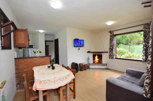 a living room with a table and a fireplace at Chalés dos Alpes in Monte Verde