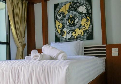 a bedroom with a white bed with a picture on the wall at CC Beach Resort in Khanom