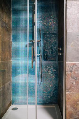 a bathroom with a shower with blue tiles at La Maison de Campagne in Kilmuir