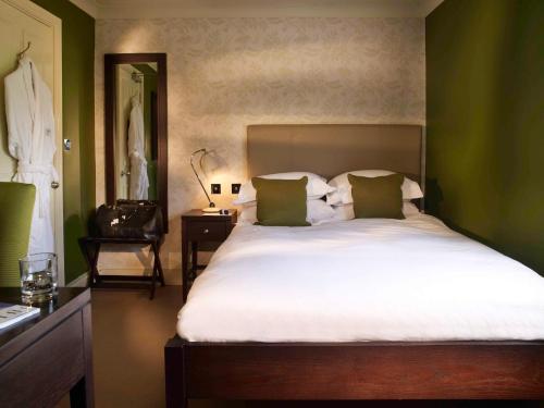 a bedroom with a large bed with green walls at Stoke Place- Part of the Cairn Collection in Slough