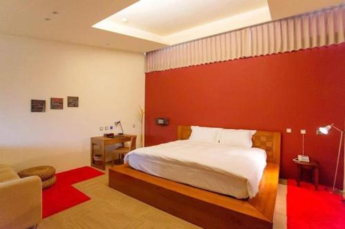 a bedroom with a bed and a red wall at Sheng Tu Villa in Hengchun