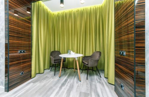 a table and chairs in a room with green curtains at Luxury Apartments Arena Guliver in Kyiv