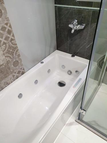 a white bath tub with a shower and a sink at Хотел ЦЕНТРАЛ in Stara Zagora