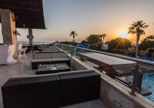a hotel rooftop with a swimming pool and the sunset at Ramada Resort Dead Sea in Sowayma