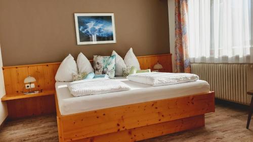 1 dormitorio con cama de madera y almohadas blancas en Gästehaus Scharler, en Neukirchen am Großvenediger