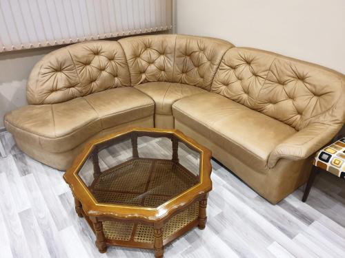 a brown leather couch in a living room with a table at Хотел ЦЕНТРАЛ in Stara Zagora