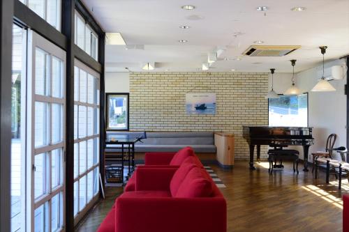 a living room with a red couch and a piano at Sea Tiger Island Inn Shodoshima in Shodoshima