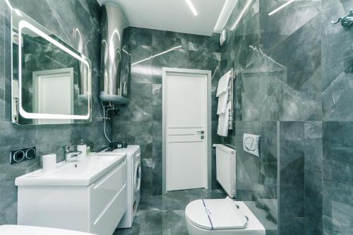 a bathroom with a sink and a toilet and a mirror at Luxury Apartments Arena Guliver in Kyiv