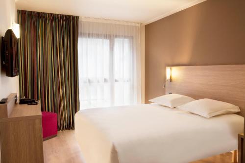 a bedroom with a large white bed and a window at Escale Oceania Orléans in Orléans